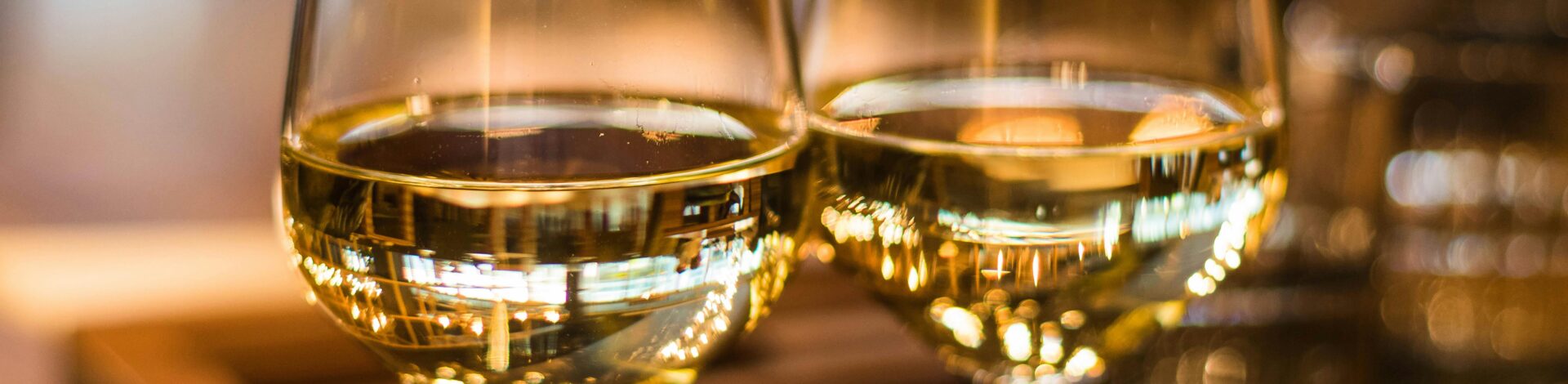 Two elegant wine glasses filled with white wine, captured with a beautiful bokeh effect.