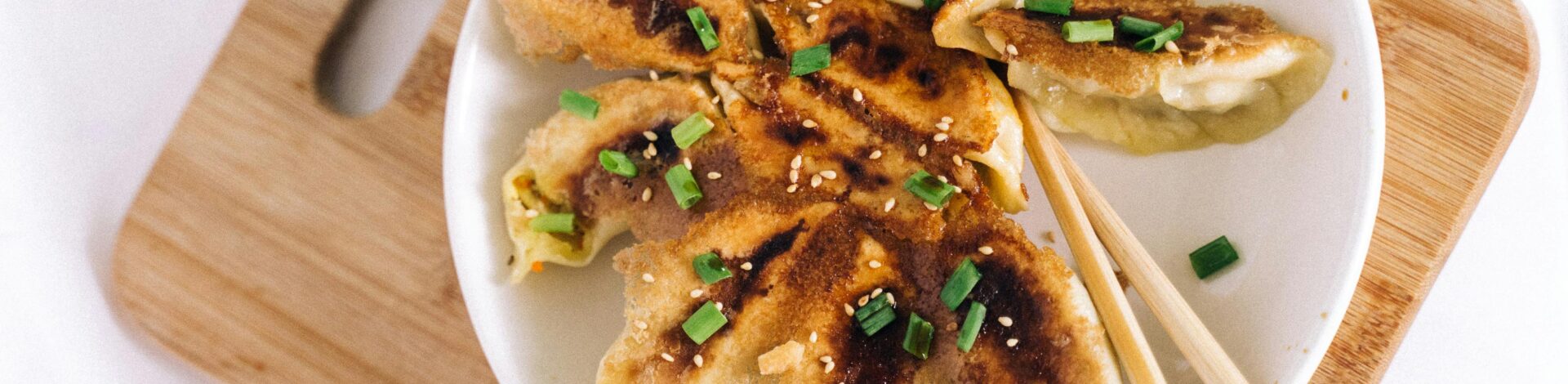 Tasty homemade fried dumplings served on a wooden board with chopsticks.