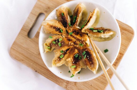 Tasty homemade fried dumplings served on a wooden board with chopsticks.