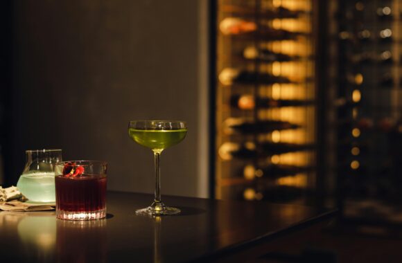 A variety of colorful cocktails on a bar table in a dimly lit setting, exuding luxury and sophistication.